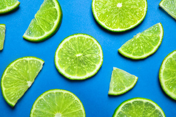 Juicy fresh lime slices on blue background, flat lay