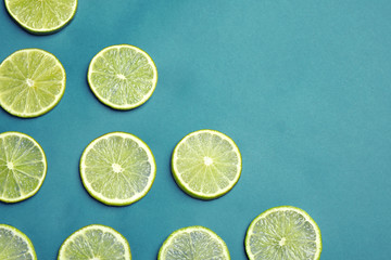 Juicy fresh lime slices on blue background, flat lay. Space for text