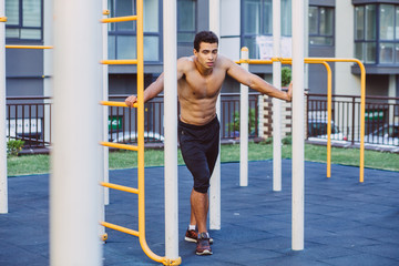 Sportsman resting on sportsground after workout. Athlete man looking away, relaxinf after exercises. Sport, lifestyle and people concept.