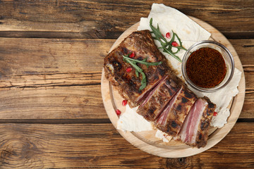 Delicious grilled ribs served on wooden table, top view