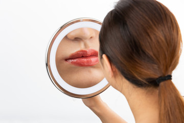 鏡で唇を見る女性