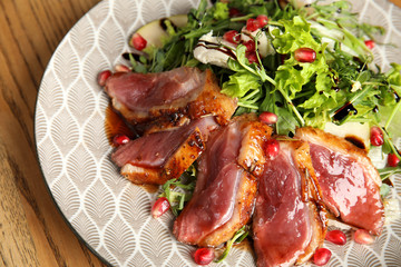 Delicious salad with roasted duck breast served on wooden table, closeup