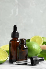 Lime essential oil and citrus fruits on marble table