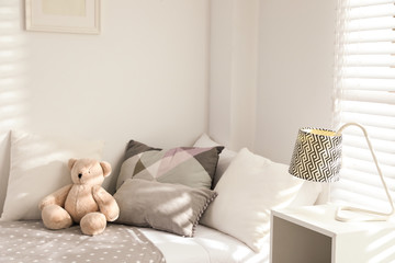 Teddy bear on bed in modern child room. Interior design