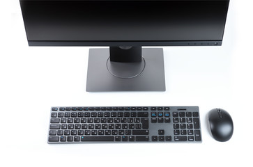 Black monitor with a gray keyboard and mouse on a white background. View from above.
