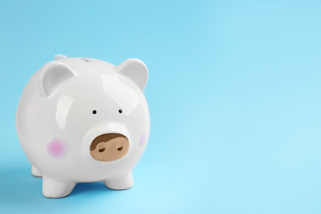 White piggy bank on light blue background. Space for text