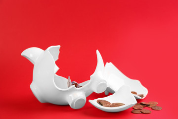 Broken piggy bank with money on red background