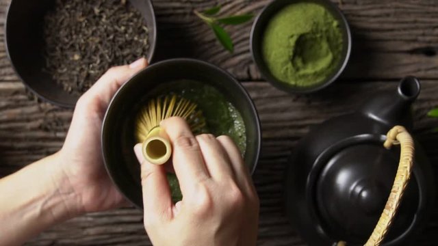 Preparing Japanese organic matcha green tea powder in the black bowl with wire whisk on wooden table, Organic product from the nature for healthy with traditional style