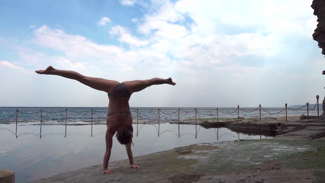 girl doing a handstand in bikini near the pool in nature