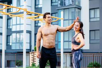 Sportsman and his girlfriend pointing fingers at camera on sportsground after workout. Athlete...