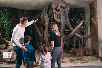 Family in the Museum. A family stands in front of a mammoth skeleton in the Museum of paleontology.