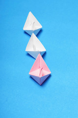 Leadership Concept: Pink paper ship among white with a blue background