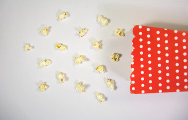 top view of popcorn in pattern with a white dotted red color popcorn box on white background