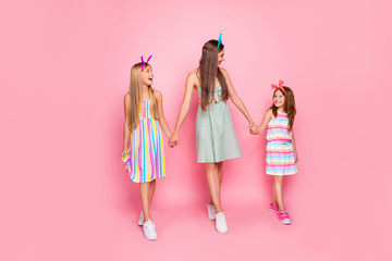 Full length photo of lovely girls with headbands holding hands looking wearing skirt dress isolated over pink background