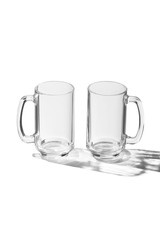 Detailing shot of a pair of classic design beer mugs with thick glass handles. The beer glasses are isolated on the white surface with shadows.  