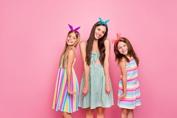 Portrait of cheerful girls with colorful headbands smiling posing wearing skirt dress isolated over pink background