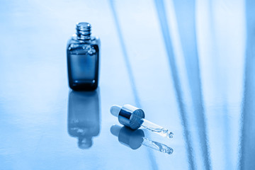 Open bottle with fluid collagen of hyaluronic acid. Toned blue. Close-up.