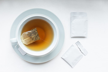 Cup with tea and mockup tag. Teabag pack copyspace mockup advertising design. Tea pack on white background. White tea sachet mock up.