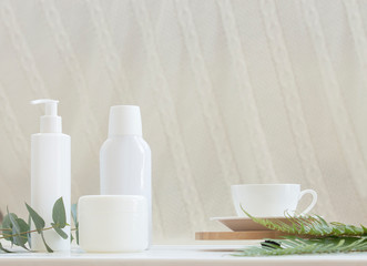 Natural cosmetics and leaves of fern and eucalyptus on a light background.