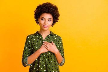 Portrait of calm inspired afro american girl touch her chest palm believe feelings look good...