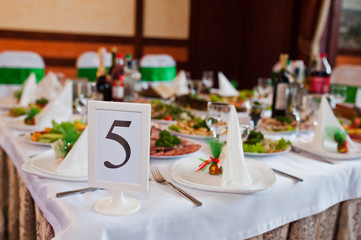 Beautiful wedding set decoration in the restaurant. Number 5 on table.