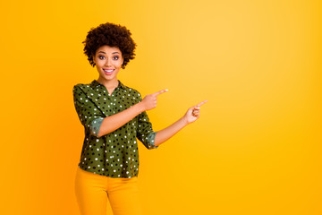 Photo of funny dark skin curly lady indicate fingers side empty space advising customers amazing...