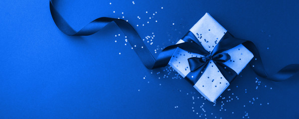 Gift or present box and gold stars confetti on black table top view. Flat lay composition for birthday, mother day, black friday sale, xmas, christmas, new year or wedding.