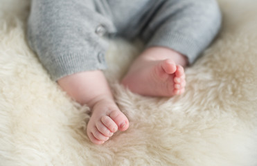 A beautiful soft delicate warm young baby foot photographed with a shallow depth of field. gentle calm colours and feel. baby care and well being. babies feet on a cream fur rug.