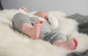 A beautiful soft delicate warm young baby foot photographed with a shallow depth of field. gentle calm colours and feel. baby care and well being. babies feet on a cream fur rug.