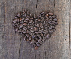 heart shaped making with beans of coffee arranged on a rustic plank