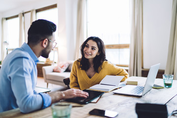 Beautiful lady sitting in bright room and talking with colleague