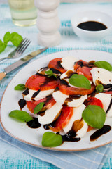 Fresh delicious Caprese salad with mozzarella cheese, tomatoes, Basil and balsamic sauce on a rustic background. Vertical photo