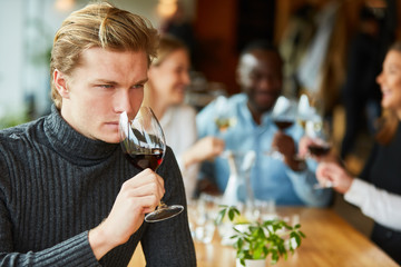 Young man smells at a glass of red wine