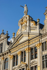 Facade of one of the buildings at Grand Place Brussels, Belgium. Detailed with a lot of gold ornaments on a blue sky day.