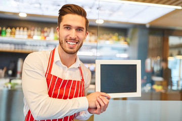 Waiter holding blank chalkboard in bar or restaurant