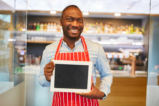 African waiter is holding blank signboard