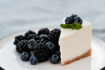 slice of cheesecake with blueberries and blackberries on a gray background. Minimalism
