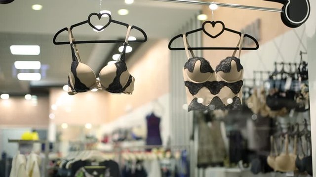Female lingerie store showcase. Bras on hangers. High-quality women underwear boutique. Different styles and patterns of bras. Attractive romantic and home clothes shop.