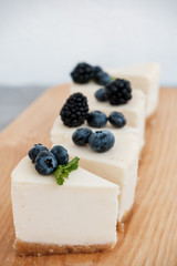 slices of classic cheesecake decorated with berries on a wooden board