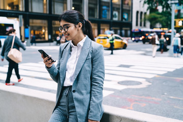 Cheerful female entrepreneur leaning on railing and typing