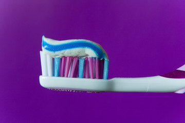A multi-colored toothpaste is applied to a multi-colored toothbrush.