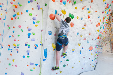 Sportsmen climbs boulder in a gym. A successful man climbing on climbing wall.
