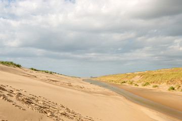 Fototapeta na wymiar Inside the wet dune valley of the Hondsbossche Duinen under a cloudy sky