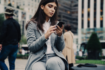 Confident woman in formal clothes using smartphone
