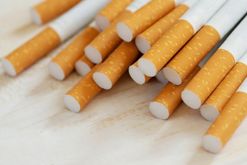 image of several commercially made pile cigarette on white wooden background. or Non smoking campaign concept, tobacco pattern top view.