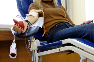 Blood donation, girl donor in chair with a red bouncy heart in hand. Concept of donorship, transfusion, health care