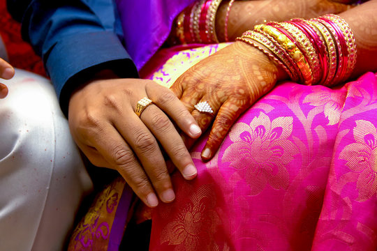 Indian Groom putting a wedding engagement ring on finger of Bride.