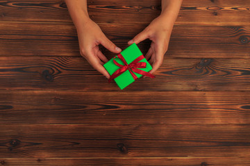gift in female hands on a wooden background top view. - Image