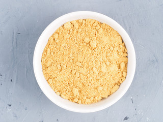 Dry ginger in a white bowl on a gray concrete background. Healthy eating concept