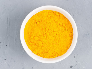 Turmeric in a white bowl on a gray concrete background. Healthy eating concept